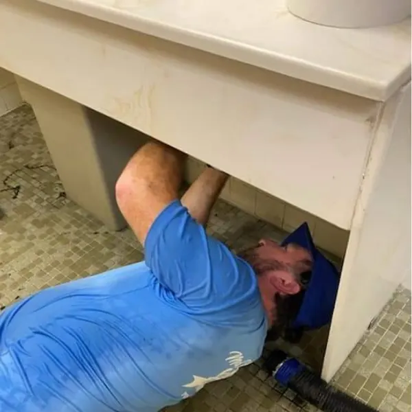 Technician repairing pipes underneath a bathroom sink